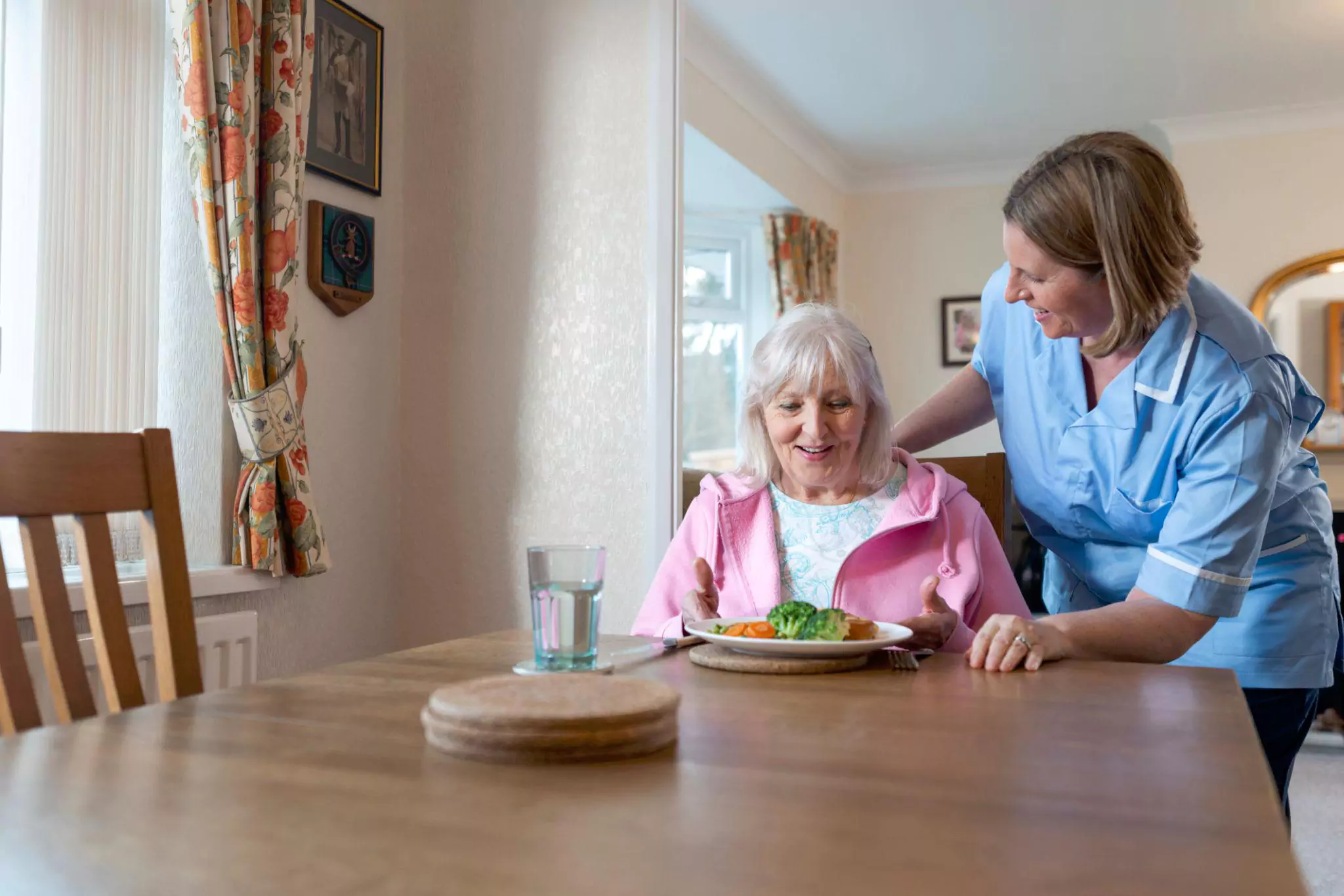 Senior resident enjoying a nutritious meal with caregiver support